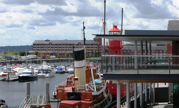a view of Swansea marina with lots of boats on the water. you can see the viewing deck upstairs at the museum where visitors can look out onto the wat